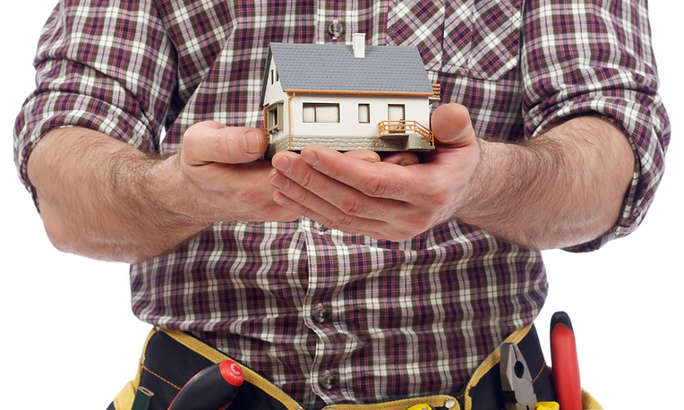 T茅cnico de reparaci贸n de electrodom茅sticos con camisa a cuadros y cintur贸n amarillo, con una casa blanca en miniatura en las manos