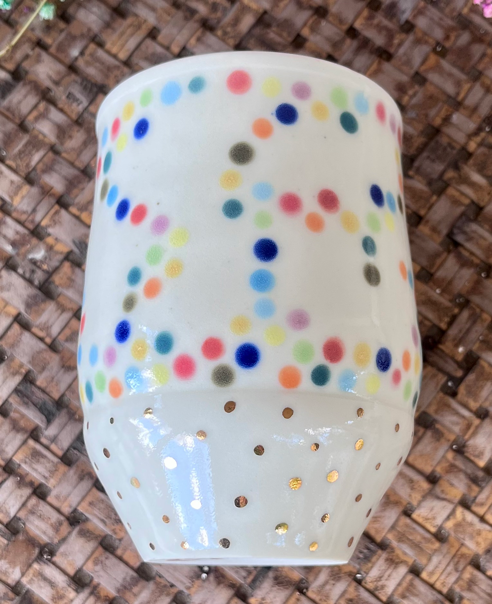 Thumbnail: Porcelain cup with red interior glaze and rainbow polka dot exterior glaze with gold luster accents.