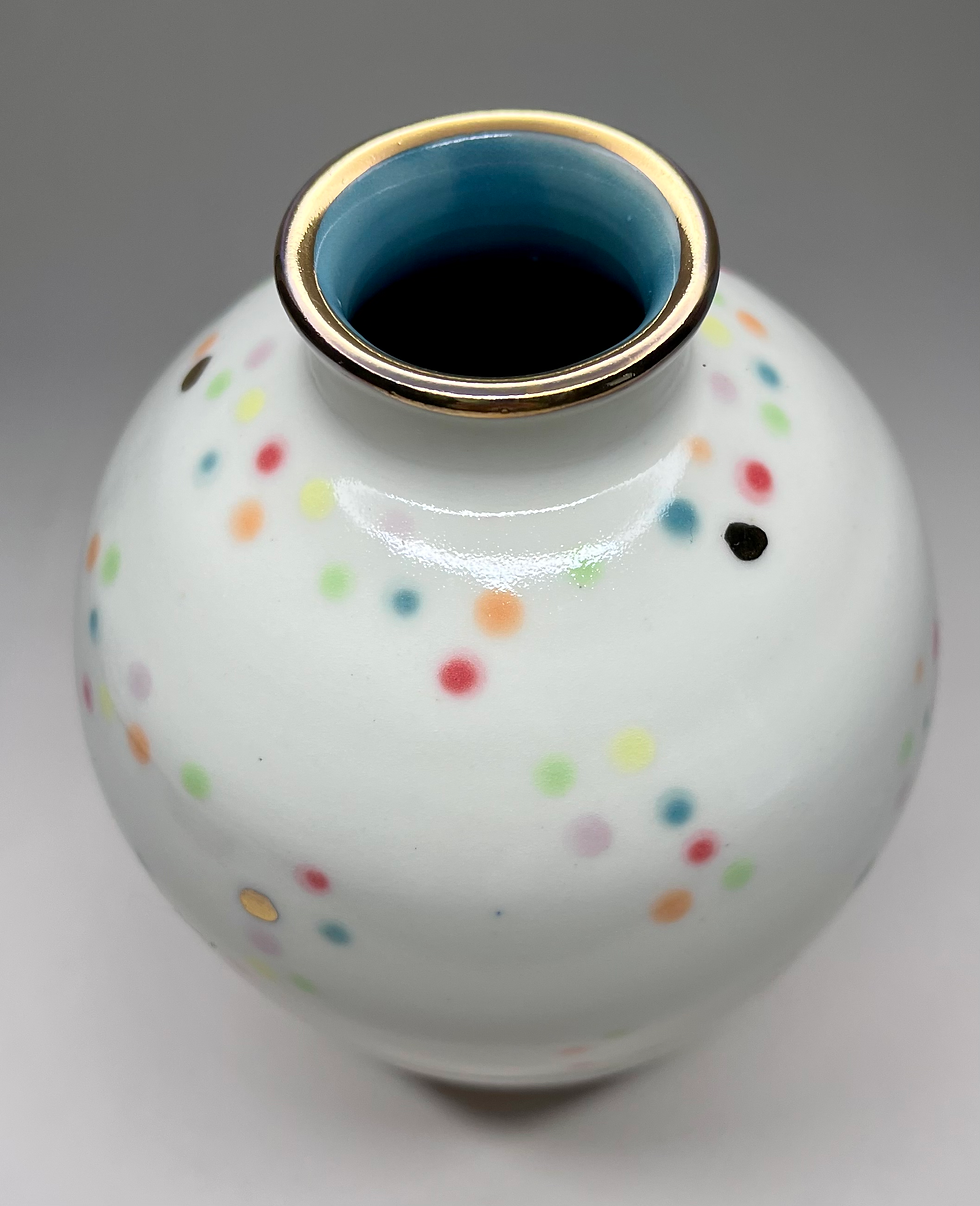Porcelain ceramic vase with rainbow polka dots. Three-quarter view of pottery vase from top.