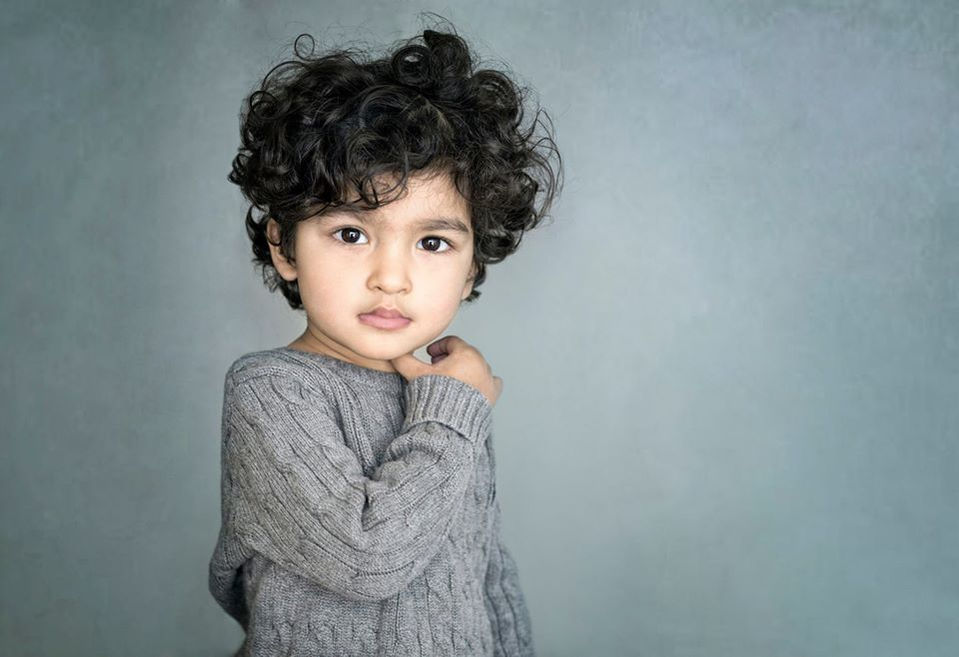 Fine art portrait of a boy in grey jumper on a blue background