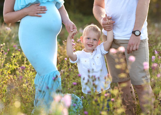 a boy holding his dad and pregnant mum's hand