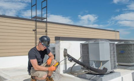 HVAC technician working on rooftop units checking for leaks with HVAC equipment