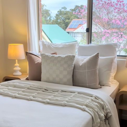 Neutral bedroom styling with layered bedding, timber furniture and soft décor by Nathalia Rico Interiors.