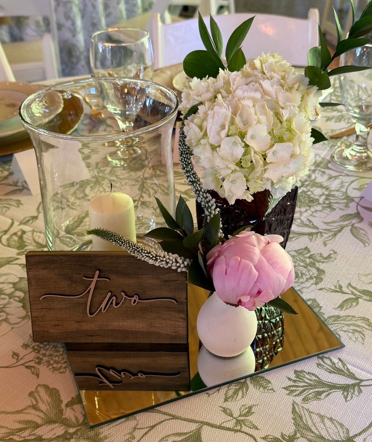 Reception centerpiece featuring peonies, hydrangea, greenery, and Veronica. Mirror and candle brightened the centerpiece