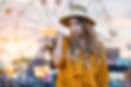 Bare feet woman walking on the beach holding sandals in hand at sunset time near amusement