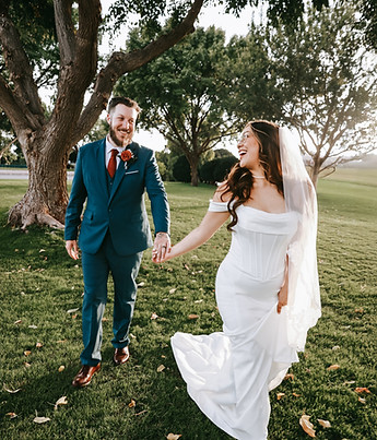 Bride and groom cheerfully walk through a park holding hands and laughing in Boulder City, NV