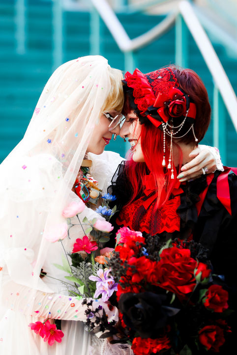 Romantic portrait of two brides touching foreheads and smiling while holding colorful bouquets during their alternative Las Vegas wedding.