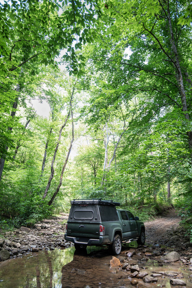 Tacoma with a Madix Drift camper doing a river