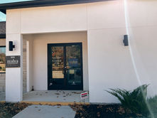 The entrance of the modern building Naba Style Nails, stylish wall lights, a sleek design, and simple landscaping, all contributing to a welcoming atmosphere.