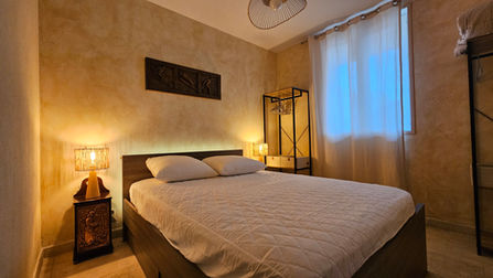 La chambre principale invite au calme, avec son lit confortable en 140 et son éclairage tamisé. Le rideaux clair et les lampes en fibres tressées renforcent l’ambiance cocooning propice au sommeil et au ressourcement.