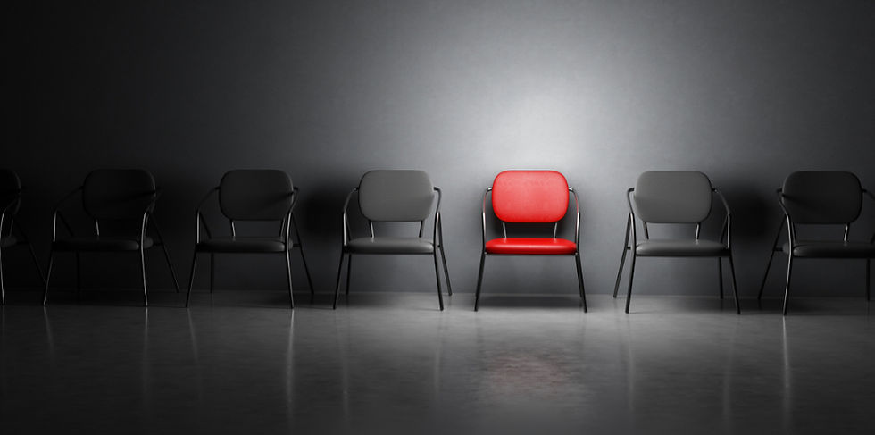 Red chair stands out among black chairs in a row against a dark wall. The spotlight highlights the red, creating a striking contrast.