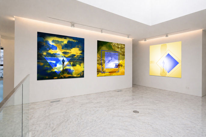 "The Horizon Within" triptych displayed in a contemporary gallery, featuring three blue-and-gold artworks exploring distance, arrival and reflection.