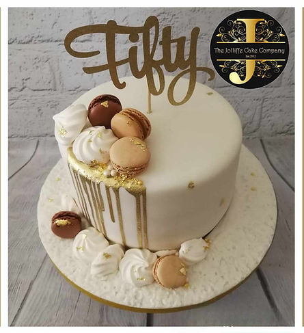Round drip cake with gold drip, macarons and gold fifty script cake topper