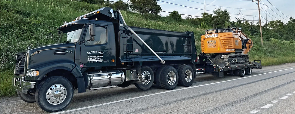 Excavator being hauled on a dump truck for an excavation project in Rostraver, PA by Skowronek Landscaping & Excavating.