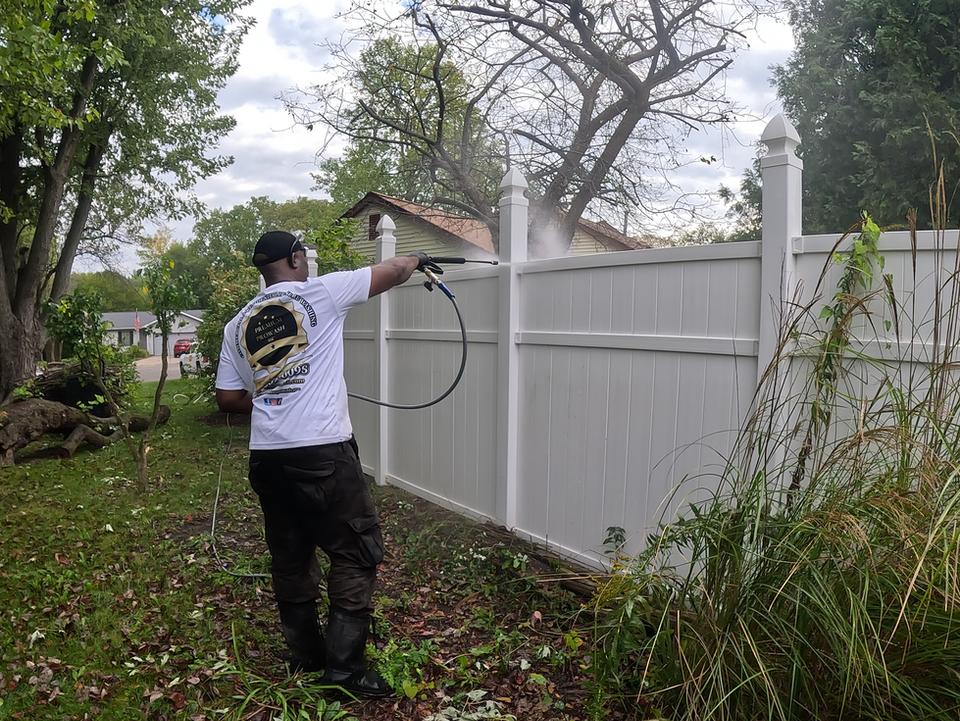 Worker pressure washing a vinyl fence at a residential home.