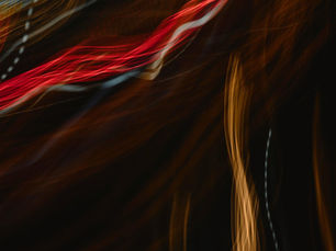 Abstract image with vibrant red, orange, and white light trails on a dark background, creating an energetic and dynamic visual effect.