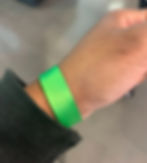 Kimi's wrist with a bright green fabric wrist band next to the edge of the sleeve of her black jacket.