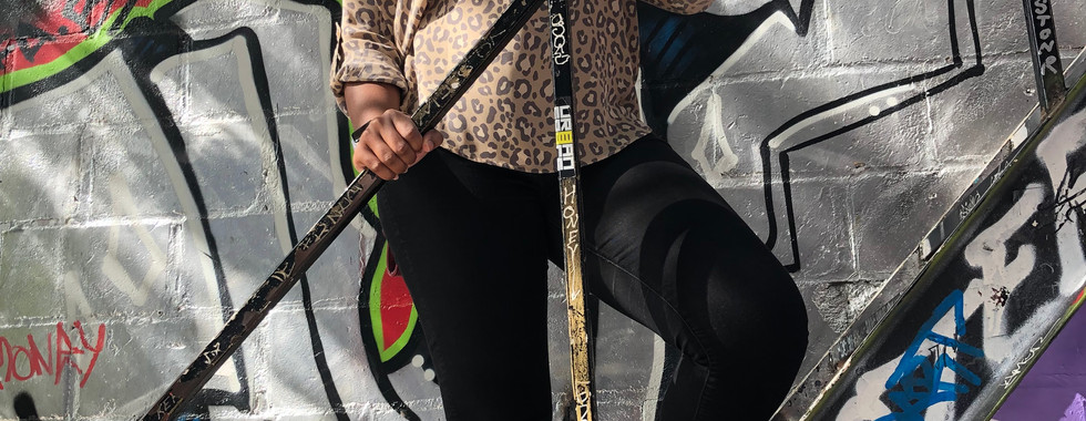 Graffiti Alley picture of Kimi posing on a staircase in her black jeans and leopard print long-sleeve shirt with black wavy box braids.