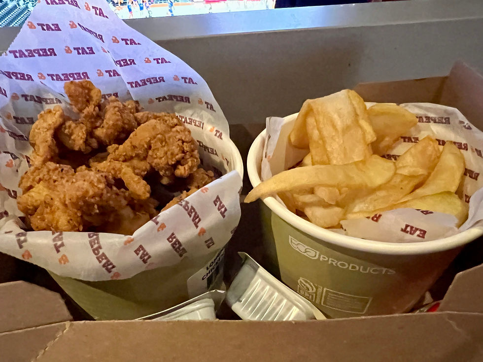 Left: fried chicken bites in a green wide opening paper cup and parchment paper lining. Right: fries in a cup like the chicken bites.
