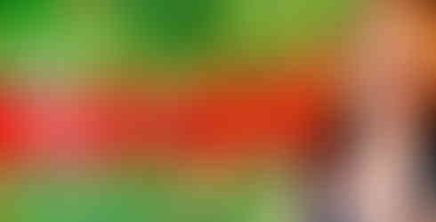 Kimi in a black top smiles in front of the neon red Bacardí sign against a green tropical foliage background.