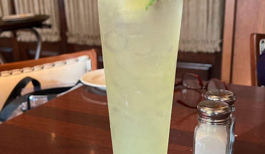 Pineapple Refresher. Pale yellow drink with a pineapple wedge and mint leaves on top.