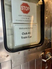 Adults-only signage. Upper sign has an image of a stop sign with the words "Adults-only Club 41 passengers only" below the image. Lower sign says "Welcome to the Club 41 Train Car".