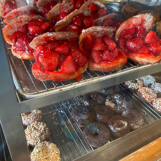 The Donut Man fresh strawberry donuts in the display window. Glazed donuts cut in half and stuffed with fresh, ripe whole strawberries with a thin coating of strawberry glaze.
