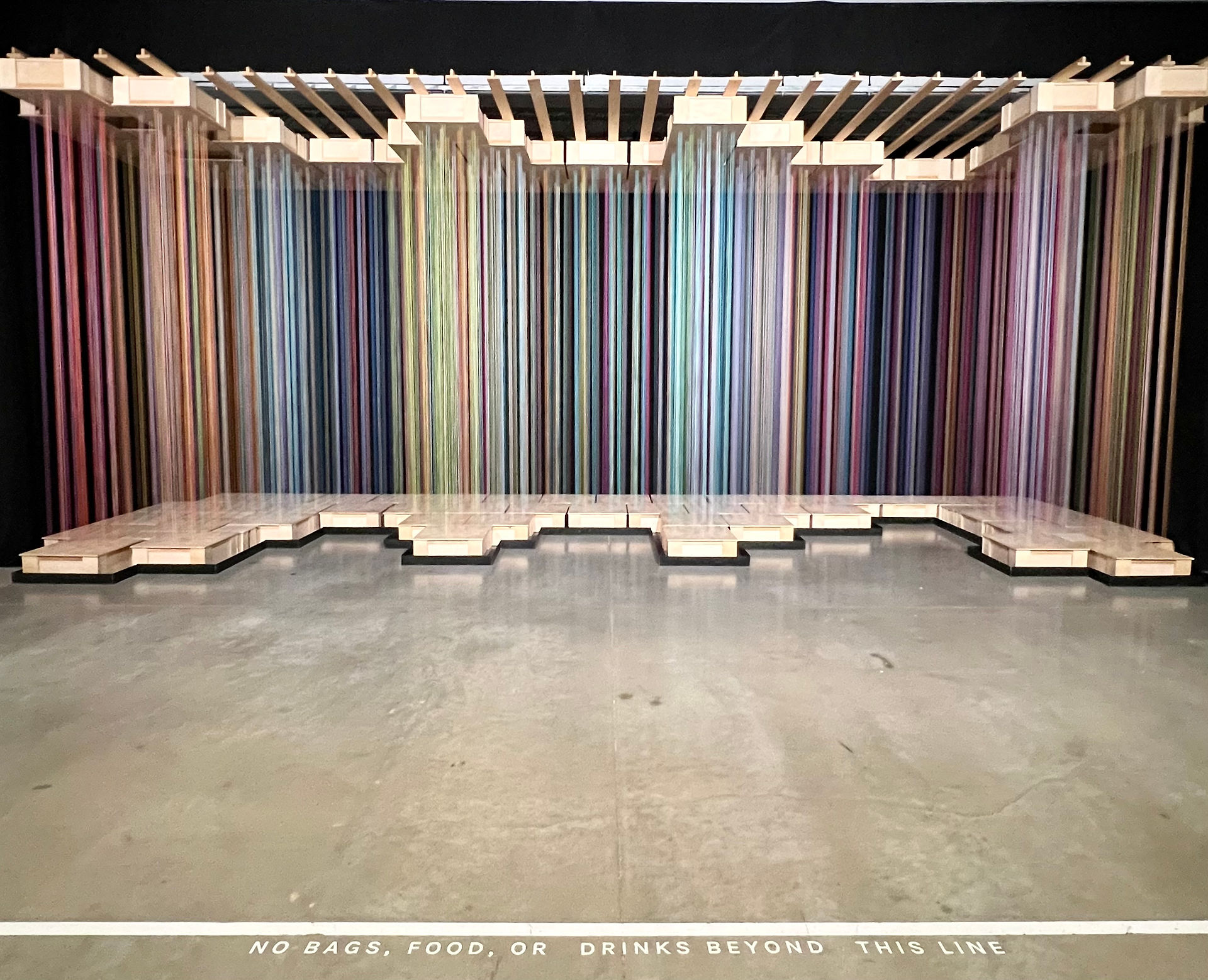 Sweet Spot by Causey and Daniel. Multi colored string hanging vertically between upper and lower wooden platforms.