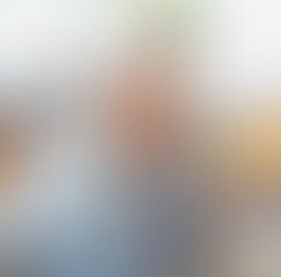 Personne assise à domicile tenant ses lunettes et se touchant le visage en raison d’une gêne visuelle.