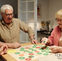3 seniors souriants jouant aux jeux de société avec plateau de jeu gros caractères