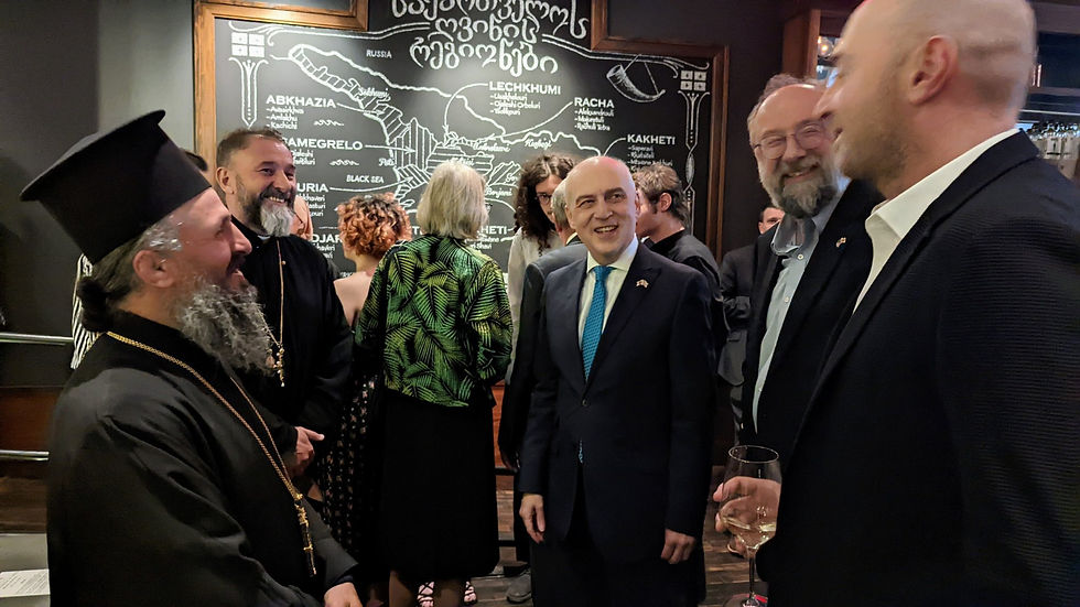 There are five men standing in a circle having a conversation