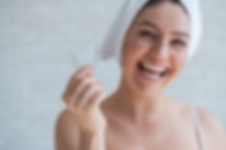 A woman with a towel on her head holds a whitening mouth guard for teeth. The girl aligns
