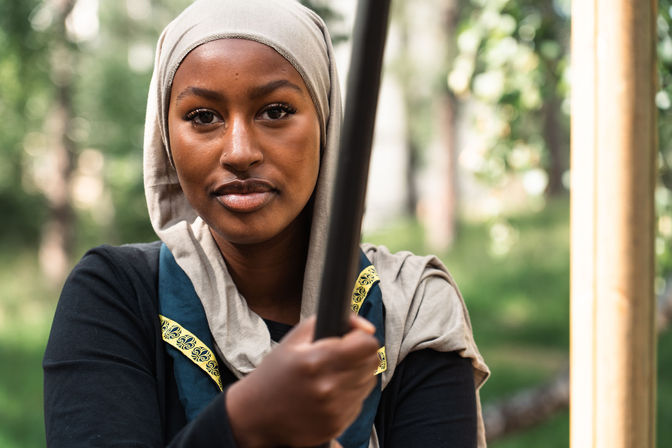 Närbild och utomhusporträtt på en leende kvinna i hijab fotograferad i en grönskande skogsmiljö.