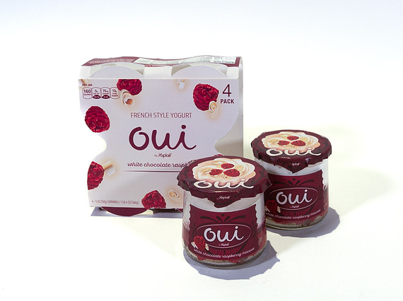White chocolate raspberry mousse yogurt with the carton standing up behind two jars of yogurt with logo and label
