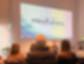 An image of Christoph standing in front of a group during the Manchester Mindfulness Festival (October 2023), holding a mic, smiling.  