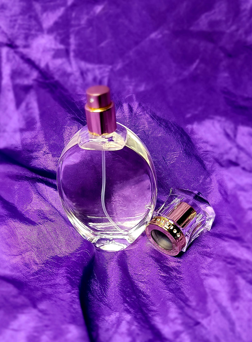 Clear perfume bottle on purple fabric, Women's Perfume, close-up shot, elegant setting