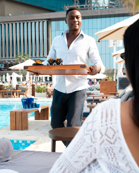 Man serving food by a poolside.