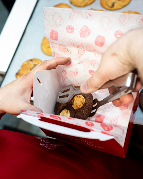 Hands placing cookies in a red box.