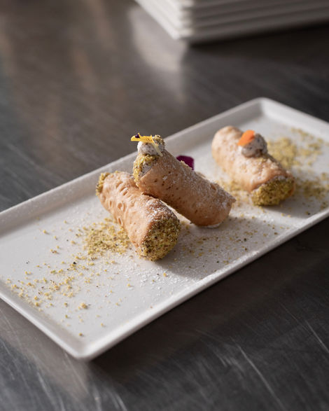 Two cannoli on a rectangular white plate.