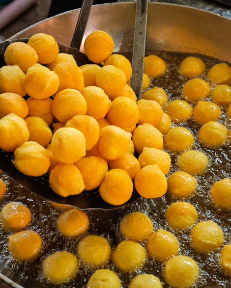 Golden balls being fried in hot oil.