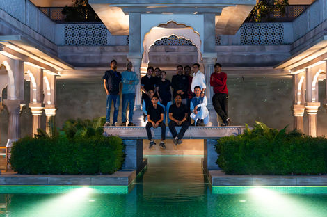 Group of people posing by a pool at night.