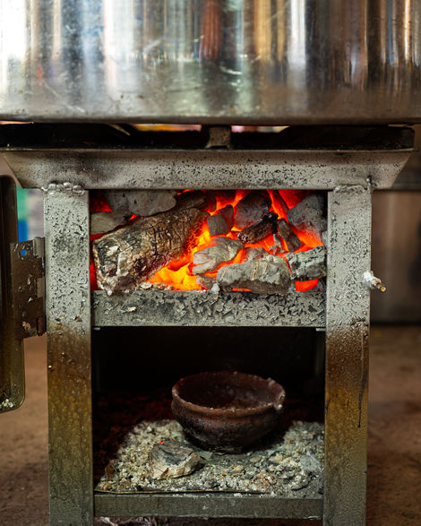 Wood-fired stove with burning logs and glowing embers.