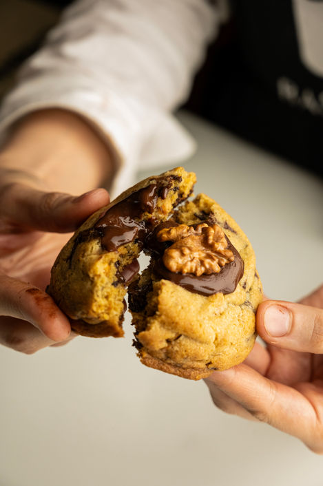 Hands breaking a chocolate-filled cookie with walnut.