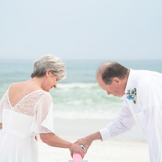 Couple pouring sand into a vessel symbolizing unity.