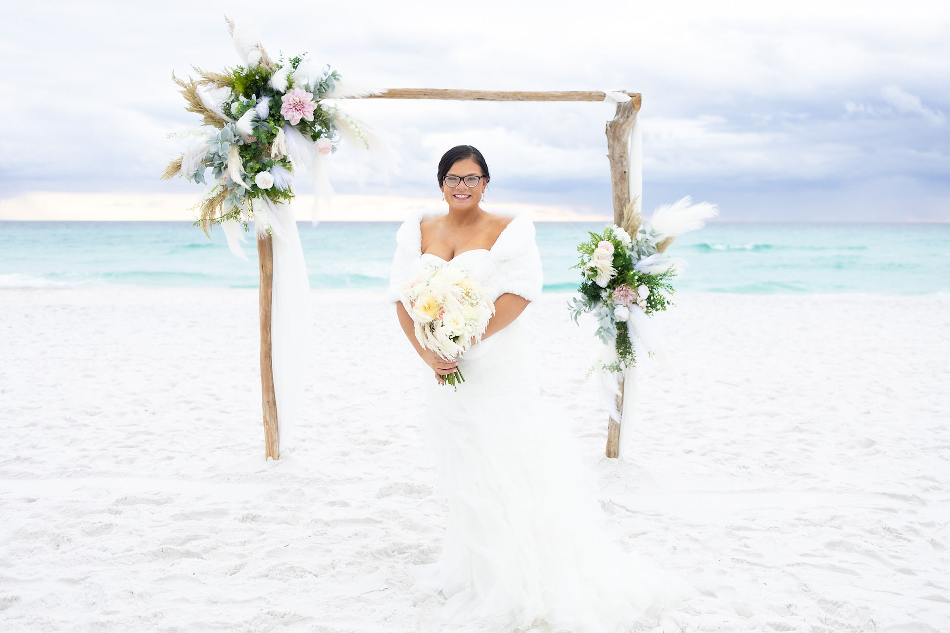 Bride smiling with a Florida beach in the background and a wedding arch