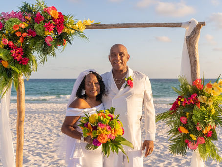 Colorful wedding florals with couple standing on the beach at a destination wedding location.