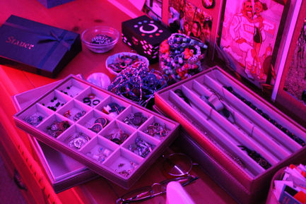 a photo with magenta lighting of jewellery spilling out of containers