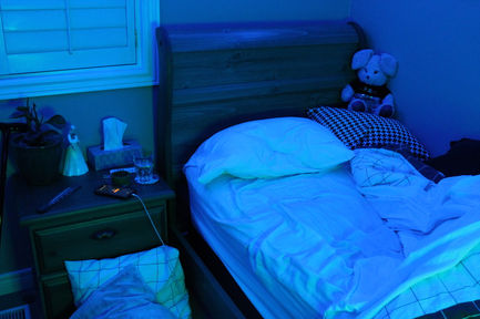 a photo with blue and green lighting of an unmade bed