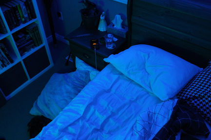 a photo with blue and green lighting of an unmade bed