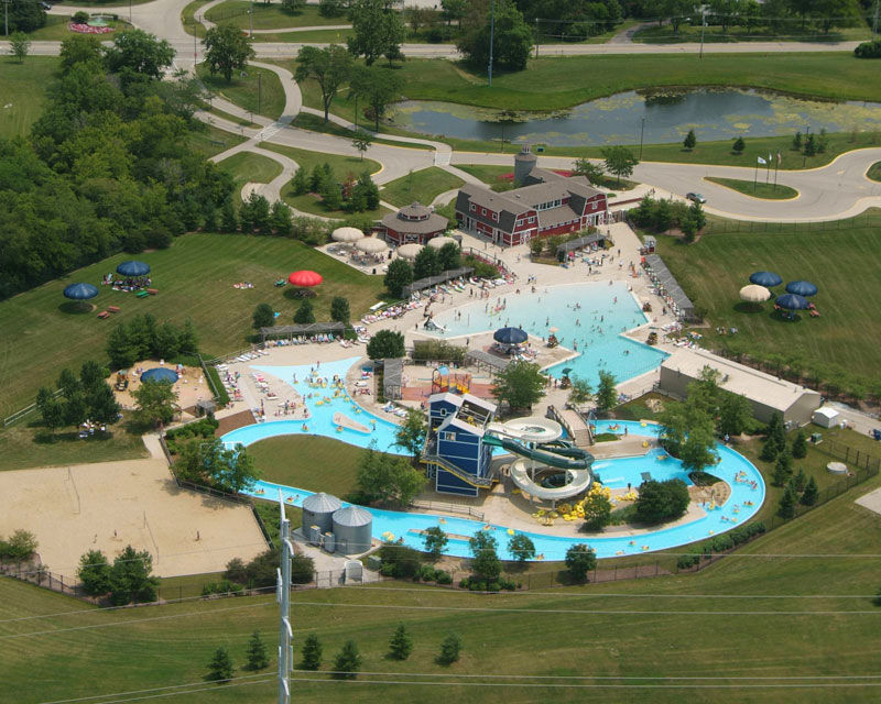 Outdoor Arial photo of Splash Country Water Park featuring a lap pool, zero depth entry pool, water slides, lazy river, red barn looking building and more.